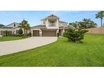 Charming two-story home with a large manicured front lawn, a three-car garage, and a second-story balcony at 4607 Los Robles Ct, Palmetto, FL 34221