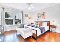 Bright bedroom boasts wood floors, ceiling fan, stylish decor, and window providing ample natural light at 5730 Imperial Ky, Tampa, FL 33615