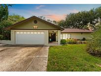 Charming one-story home featuring a well-maintained lawn, attached garage, and front porch at 945 Winding Oaks Dr, Palm Harbor, FL 34683