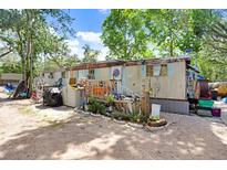 Exterior view of an older mobile home featuring a yard, trees and aged siding at 10044 Oana St, New Port Richey, FL 34654