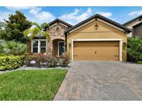 Charming home with brick paver driveway and two-car garage, complemented by lush landscaping at 11613 Sweet Tangerine Ln, Tampa, FL 33626