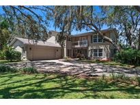 Charming two-story home with a balcony, attached garage, and driveway partially shaded by mature trees at 1310 Rustlewood Dr, Brandon, FL 33510
