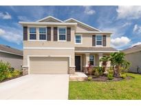 Charming two-story home featuring a two-car garage, well-maintained lawn, and meticulously landscaped front garden at 16972 Oval Rum Dr, Wimauma, FL 33598