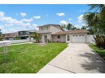 Two-story home with a lush green lawn, a long driveway leading to the attached garage, and a beautiful blue sky at 1712 Azalea Ct # B, Oldsmar, FL 34677