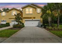Charming yellow townhome with a two-car garage and well-maintained landscaping at 17880 Althea Blue Pl, Lutz, FL 33558