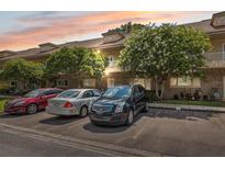 Exterior view of condo building featuring brick facade, mature trees, and parking spaces at 2192 Swedish Dr # 26, Clearwater, FL 33763