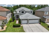 Two-story home with a gray exterior, white trim, a well-manicured lawn, and a two-car garage at 25435 Bruford Blvd, Land O Lakes, FL 34639