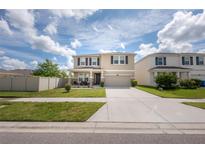 Two-story home featuring front porch seating and a two-car garage at 3052 Living Coral Dr, Odessa, FL 33556