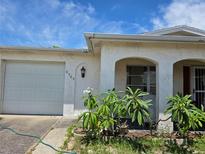 Charming home featuring a one-car garage, front yard landscaping, and an arched entryway with a security screen at 9505 Marlinton Ln, Port Richey, FL 34668
