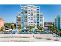 Stunning beachfront condo building featuring a mix of white and blue accents with private balconies and palm trees at 11000 Gulf Blvd # 1004, Treasure Island, FL 33706