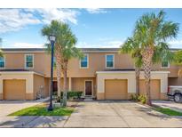Inviting townhome featuring a two-car garage, lovely landscaping, and mature palm trees at 12710 Buffalo Run Drive, Gibsonton, FL 33534