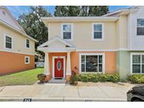 Charming two-story townhome with colorful exterior paint scheme, front yard landscaping, and welcoming red front door at 243 Alexander Woods Dr, Plant City, FL 33563