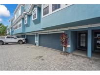 Charming condo exterior featuring blue paint, grey garage doors, and well maintained landscaping at 3111 W De Leon St # 9, Tampa, FL 33609