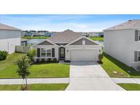 Charming single-story home with a well-maintained lawn, two-car garage, and serene lake views at 33369 Hamilton Hill Ln, Wesley Chapel, FL 33545