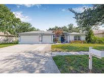 Charming single-story home featuring a well-manicured lawn, flowerbeds, and a spacious three-car garage at 34811 Arbor Green Pl, Zephyrhills, FL 33541