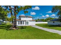Charming two-story home with a well-manicured lawn, long driveway, and white picket fence at 3513 Syracuse St, Port Charlotte, FL 33952