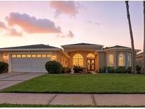 Charming single-story home with a well-manicured lawn, beautiful landscaping, and arched windows at sunset at 4428 Gevalia Dr, Brooksville, FL 34604