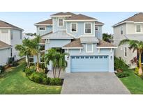 Charming three-story home features a light blue exterior, attached two car garage and beautiful landscaping at 5307 Wishing Arch Dr, Apollo Beach, FL 33572