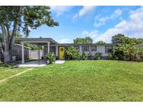 Charming single story home with a well-maintained lawn, carport, and a bright yellow front door at 5741 91St N Ave, Pinellas Park, FL 33782