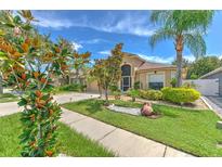 Beautifully landscaped front yard of home with mature trees, lush green lawn and inviting walkway at 7254 Parkersburg Dr, Wesley Chapel, FL 33545