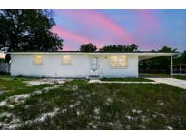 Charming single-story home featuring a fresh white exterior and cozy carport under a lovely pink and blue sky at 9259 Marler Rd, Spring Hill, FL 34608