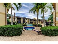 Inviting community pool and spa area surrounded by lush landscaping and palm trees at 12261 Sailwinds Dr # 203, Largo, FL 33773
