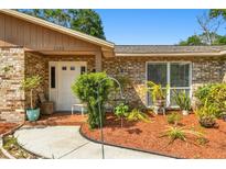 Inviting brick home featuring a front door with glass panes and a charming landscaped garden at 2222 Arch Mcdonald Dr, Dover, FL 33527
