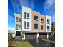 Contemporary three-story home featuring a modern design, multi-car garage, and stylish curb appeal at 324 Capri Blvd, Treasure Island, FL 33706