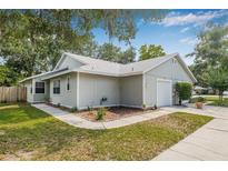 Charming single-story home with light gray siding, a single-car garage and meticulously landscaped front yard at 4532 Cedarwood Village Dr, Tampa, FL 33624