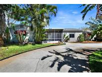 Charming single-story home featuring a welcoming screened porch and mature tropical landscaping at 4735 Baywood Point S Dr, Gulfport, FL 33711