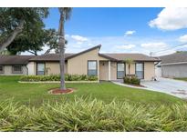 Inviting single-story home featuring a well-manicured lawn and lush landscaping at 8306 N Gomez Ave, Tampa, FL 33614