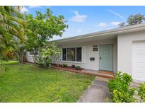 Charming single-story home featuring a quaint, light-blue front door and lush, mature landscaping at 1084 39Th Ne Ave, St Petersburg, FL 33703