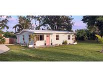 Charming single-story home featuring a well-manicured lawn, a pastel exterior, and a welcoming pink front door at 1407 Coral Ridge Dr, Punta Gorda, FL 33950