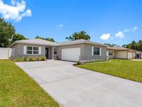 Charming single-story home with a well-manicured lawn and a long driveway leading to an attached garage at 1675 E Grovehill Rd, Palm Harbor, FL 34683