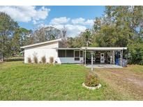 Cozy single-story home featuring a screened-in porch and carport surrounded by mature trees and a well-maintained lawn at 309 4Th Sw Ave, Ruskin, FL 33570