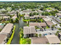 Aerial view of the community, showing lush landscaping, serene pond, and well-maintained buildings and parking areas at 3836 N Lake Dr # 121, Tampa, FL 33614