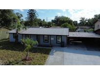 Charming single-story home boasts a metal roof, covered parking, and inviting curb appeal at 8524 Fish Lake Rd, Tampa, FL 33619