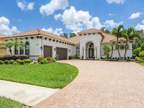 Stunning home featuring a clay tile roof, lush landscaping, and a spacious brick driveway at 1014 Stella Vara Dr, Lutz, FL 33548