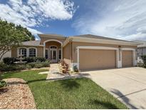 Charming single-story home with a well-manicured lawn, mature trees and a three car garage at 11610 Grove Arcade Dr, Riverview, FL 33569