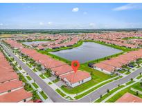 Stunning aerial view of a lakeside community with manicured lawns and red-tiled roofs on a bright day at 17415 Holly Well Ave, Wimauma, FL 33598