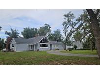 Charming home boasts a well-maintained yard, mature trees, complementing the property's inviting exterior and curb appeal at 21451 Us Highway 98, Dade City, FL 33523