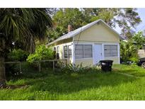 A quaint yellow single story home featuring a rectangular design, fenced yard, and overgrown lawn at 514 Woodlawn St, Clearwater, FL 33756