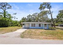 Charming single-story home featuring a light blue exterior, well-maintained lawn, and a driveway at 551 Bay St, Dunedin, FL 34698
