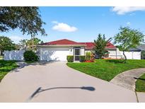Charming single-story home with a well-manicured lawn, a red roof, a paved driveway, and an attached two-car garage at 8005 Pepperidge Ln, Port Richey, FL 34668