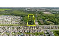 Aerial view of land for sale between neighborhood and wooded area with a yellow rectangular border at 11109 Sumner Rd, Wimauma, FL 33598