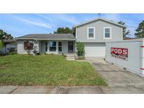 Charming two-story home with a well-maintained lawn and a brick accent wall, featuring a PODS moving container in the driveway at 15612 Farnsworth Ln, Tampa, FL 33624
