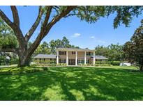 Inviting two-story home featuring a classic facade, a lush lawn, and a mature tree providing ample shade at 1681 Long Bow Ln, Clearwater, FL 33764