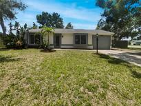 Charming single-story home featuring a well-manicured lawn and lush, tropical landscaping, plus a driveway and attached garage at 2908 Lockwood Meadows Blvd, Sarasota, FL 34234