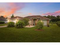 Charming single-story home with a well-manicured lawn and mature landscaping under a lovely sunset at 40449 Trotter Ln, Dade City, FL 33525