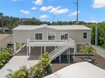 Beautiful elevated home featuring a white exterior, large deck, and well-manicured landscaping at 6924 Americana Ne Dr # 167, St Petersburg, FL 33702